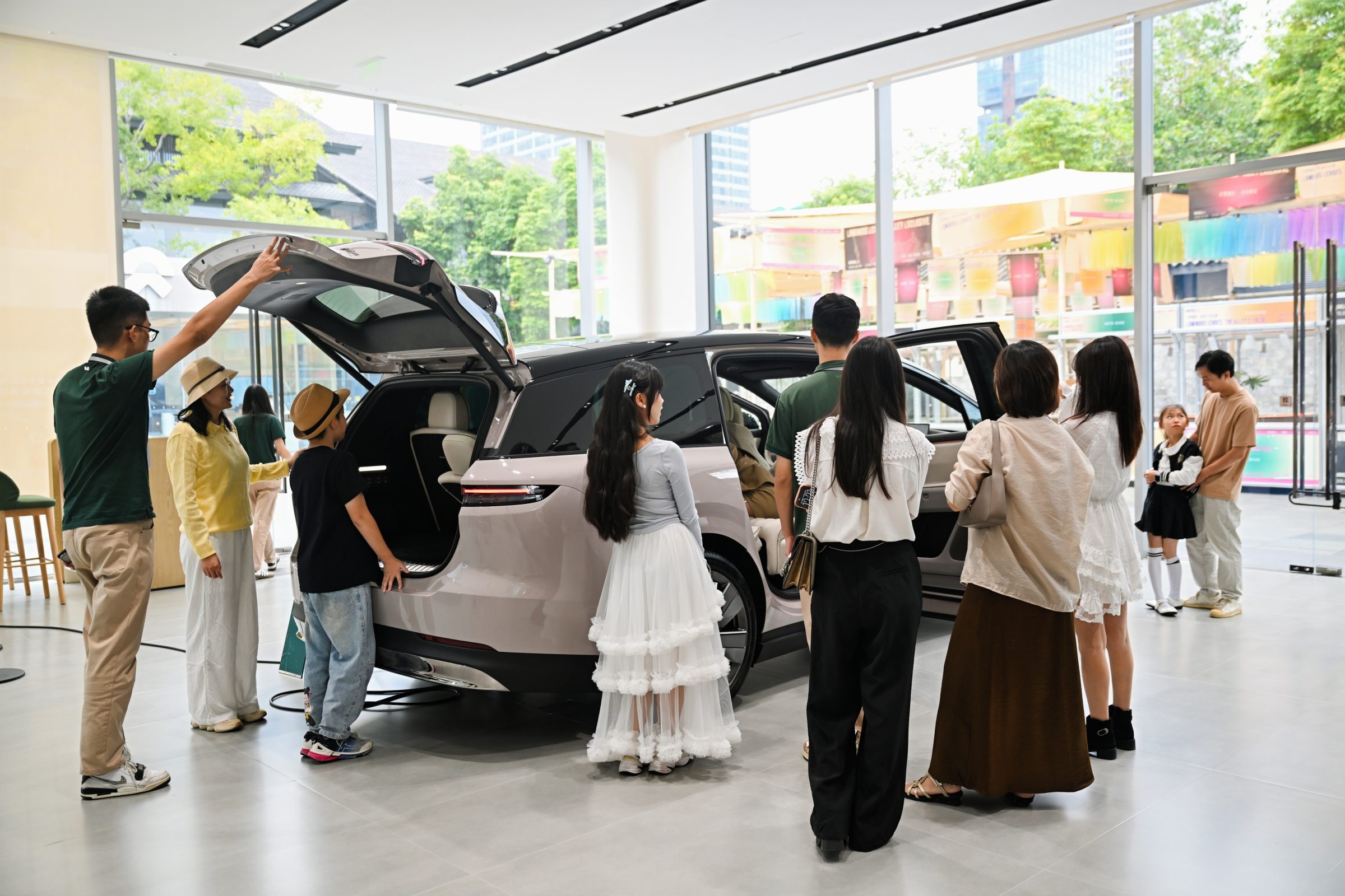 Visitors viewing a vehicle with its tailgate open inside a showroom