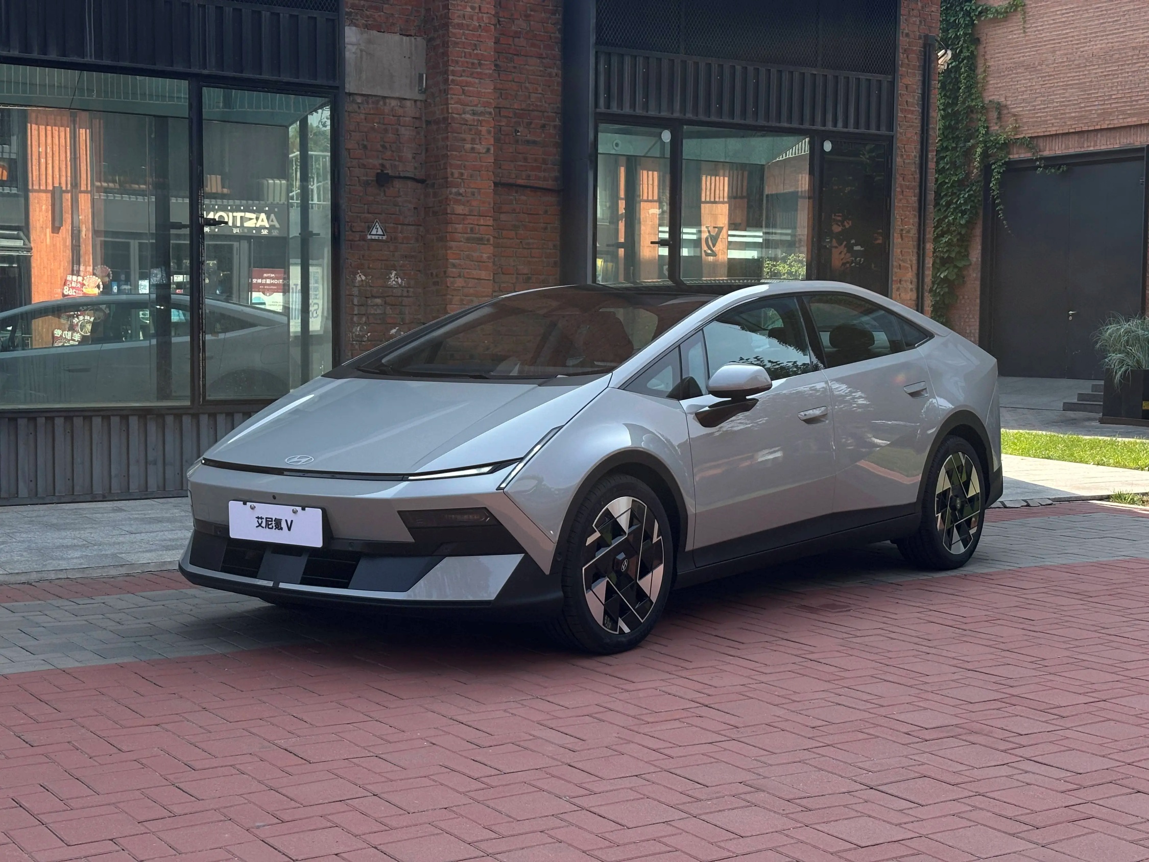 Silver Hyundai IONIQ V sedan parked outside a brick building